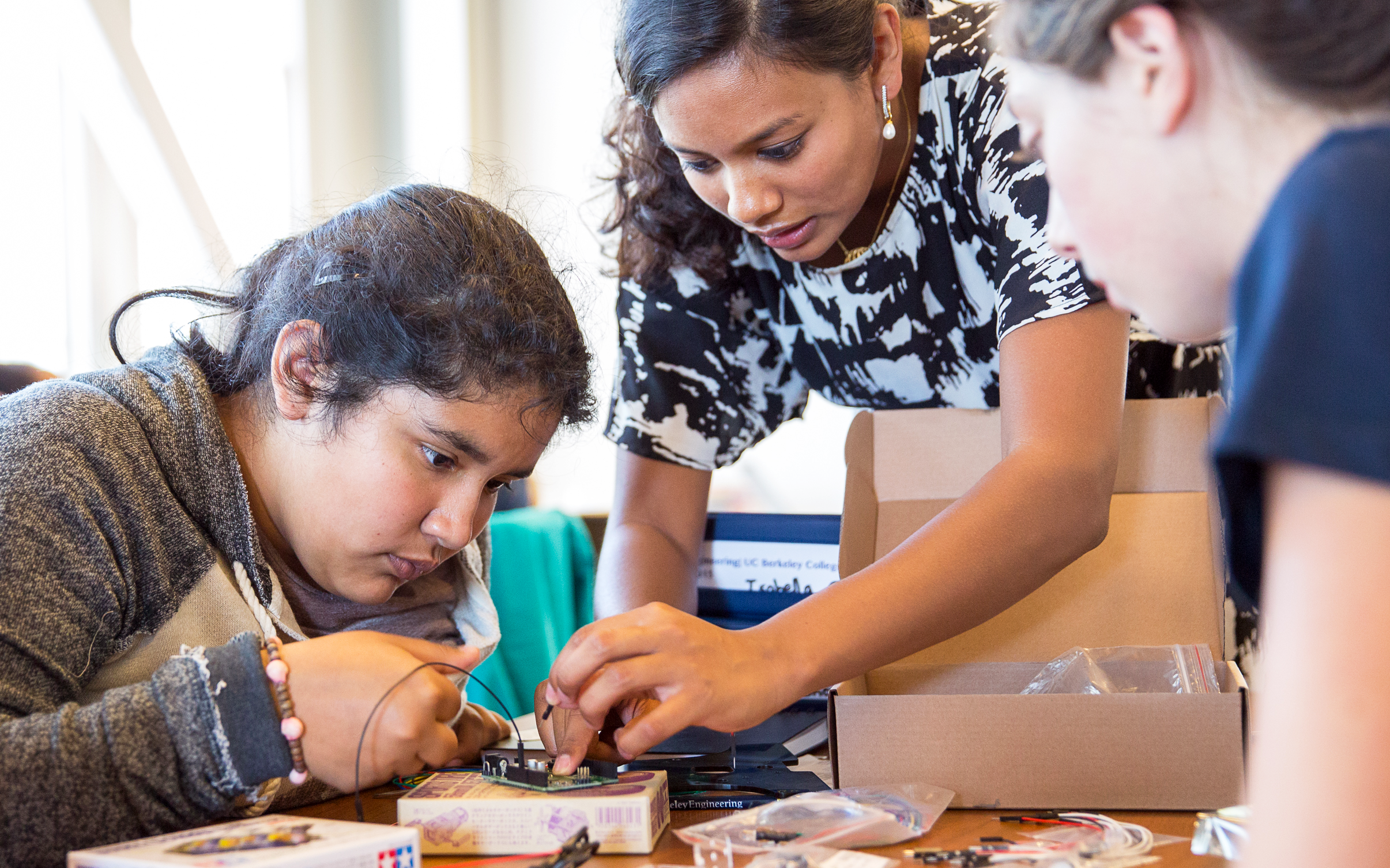 three girls working on a circuit board with wiresd