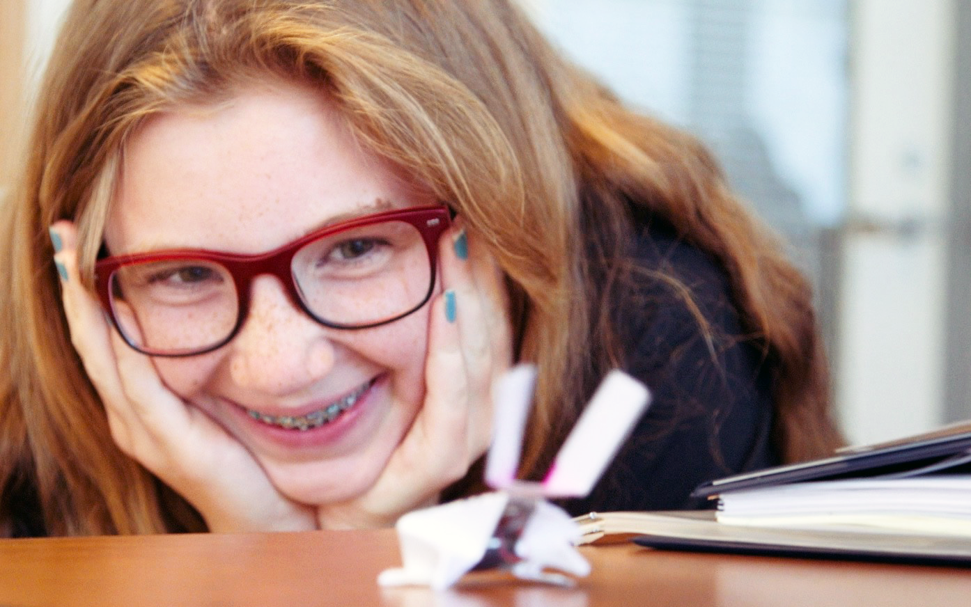 Girl smiling as she looks at her origami robot