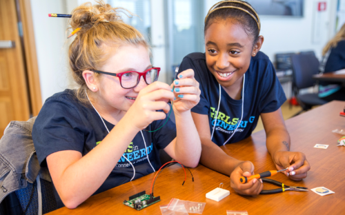 Two girls working with wires and a circuit board