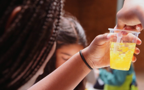 girl looking at cup with water and yellow tapioca balls